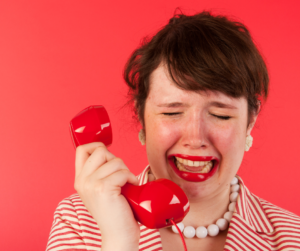 A woman cries into a red phone.